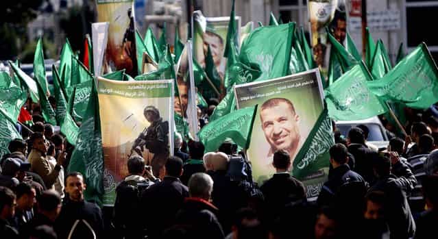 Palestinian Hamas supporters carry obituary posters of Hamas mastermind Ahmed Jabari and Hamas flags as they march in support of the people of the Gaza Strip and against Israel's military operations, in the West Bank city of Ramallah. Posters in Arabic read [Qasam brigades have made their threats and Tel Aviv gets the answer to the threat. We sacrifice with our leaders before our soldiers. We race for heaven towards God]. (Photo by Majdi Mohammed/Associated Press)