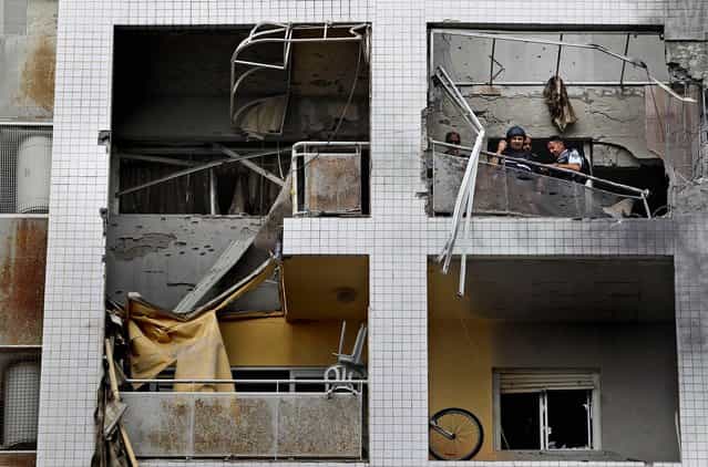 Police and civilians inspect the damage at an apartment building in the Israeli port city of Ashdod on Saturday, after it was hit by a missile fired by Palestinian militants from inside the Gaza Strip. (Photo by Tsafrir Abayov/Associated Press)