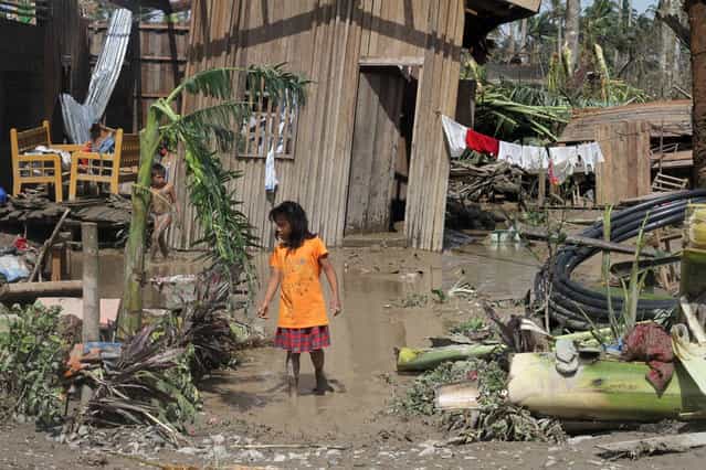 Children walk in front of their flooded home in the aftermath of Typhoon Bopha in New Bataan, Compostela Valley in the southern Philippines on December 5, 2012. The death toll from a typhoon that ravaged the Philippines jumped to 238 on December 5 with hundreds missing, as rescuers battled to reach areas cut off by floods and mudslides, officials said. (Photo by Karlos Manlupig/AFP Photo)