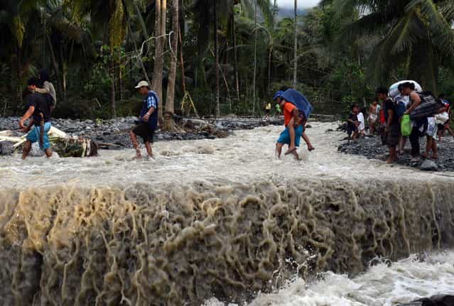 Residents cross a damaged road destroyed at the height of Typhoon Bopha in the village of Andap, New Bataan town, Compostela Valley province, on December 5, 2012. (Photo by Ted Aljibe)