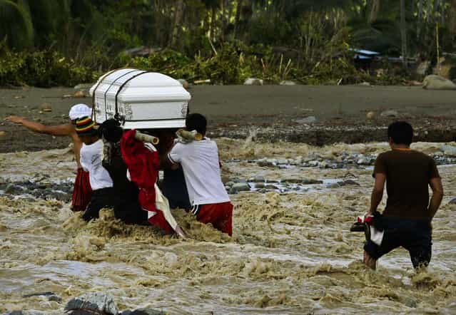 Relatives cross a river to bury their loved one, who died in a flash flood caused by Typhoon Bopha in New Bataan township in the southern Philippines, December 6, 2012. (Photo by Bullit Marquez/Associated Press)