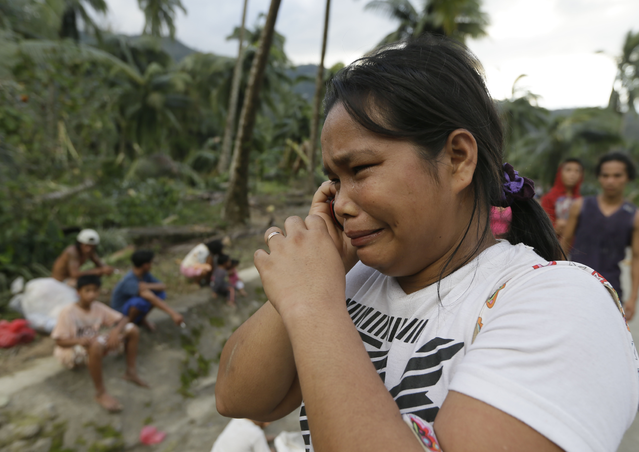 Rosalinda Pasko tearfully breaks the news to a relative of the death of her 2 of her family members at the flash flood-hit village of Andap, New Bataan township, Compostela Valley in southern Philippines Wednesday Dec. 5, 2012. Typhoon Bopha, one of the strongest typhoons to hit the Philippines this year, barreled across the country's south on Tuesday, killing scores of people while triggering landslides, flooding and cutting off power in two entire provinces. (AP Photo/Bullit Marquez)