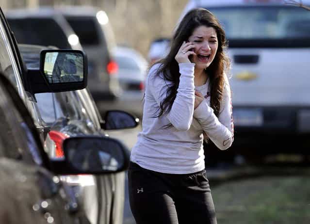 A woman waits to hear about her sister, a teacher, following a shooting at the Sandy Hook Elementary School in Newtown, Connecticut. A man killed his mother at their home and then opened fire inside the elementary school where she taught, massacring 26 people, including 20 children, as youngsters cowered in fear to the sound of gunshots reverberating through the building and screams echoing over the intercom. (Photo by Jessica Hill/Associated Press)