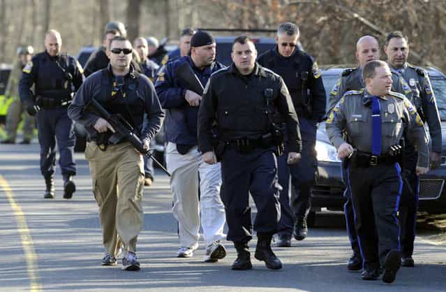 Law enforcement canvass the area following a shooting at the Sandy Hook Elementary School in Newtown, Conn., about 60 miles (96 kilometers) northeast of New York City, Friday, December 14, 2012. An official with knowledge of Friday's shooting said 27 people were dead, including 18 children. (Photo by Jessica Hill/AP Photo)
