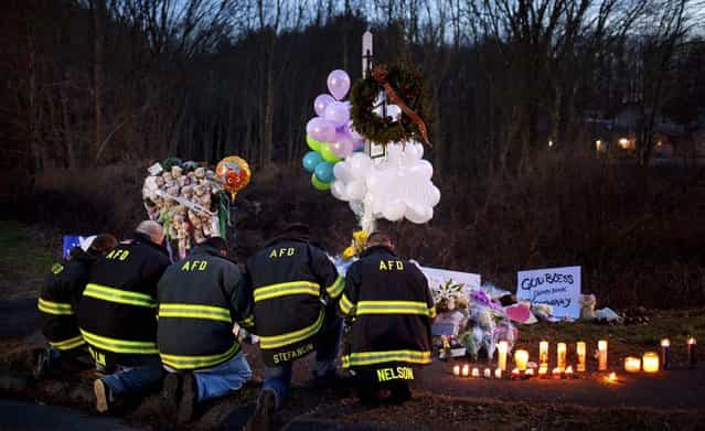 Firefighters kneel in front of a makeshift memorial for the victims of the Sandy Hook Elementary School shooting, near the school's entrance. Connecticut's chief medical examiner said Saturday it appeared that all of the children killed at the elementary school had been shot with a long rifle, as new and tragic details about the massacre of 26 people Friday emerged. (Photo by Marcus Yam/The New York Times)