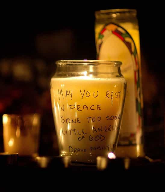 A message is seen on a candle outside St. Rose of Lima Roman Catholic Church. (Photo by David Goldman/Associated Press)