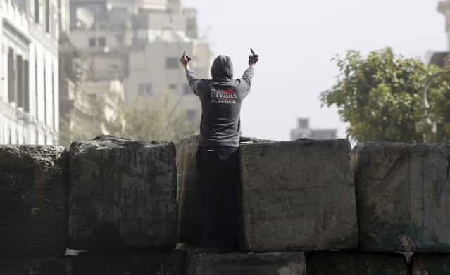 A protester on the wall towards riot police along Sheikh Rihan street near Tahrir Square in Cairo, on January 25, 2013. Opponents of Morsi and his Muslim Brotherhood allies massed in Cairo's Tahrir Square to revive the demands of a revolution they say has been betrayed by Islamists. (Photo by Amr Abdallah Dalsh/Reuters/The Atlantic)
