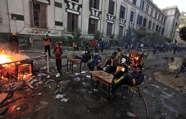 Egyptian protesters sit at school desks taken from a nearby vandalized school during clashes with riot police near Tahrir Square, on January 26, 2013. (Photo by Khalil Hamra/AP Photo/The Atlantic)