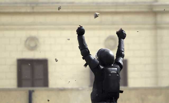 A riot police officer gestures a during clashes with protesters throwing stones at him along Sheikh Rihan street near Tahrir Square, on January 25, 2013. (Photo by Amr Abdallah Dalsh/Reuters/The Atlantic)