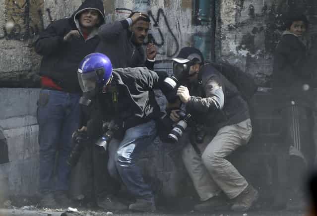 Photographers cower as protesters throw stones towards riot police along Sheikh Rihan street near Tahrir Square, on January 25, 2013. (Photo by Amr Abdallah Dalsh/Reuters/The Atlantic)