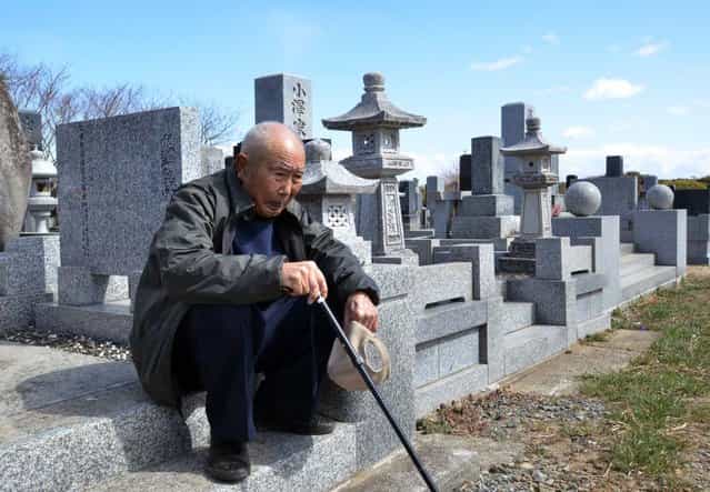 An elderly man sits as he and with his wife (not pictured) visit a cemetery to pay respects to their son who was killed in the March 2011 tsunami, in Minamisoma in Fukushima prefecture on March 11, 2013. March 11, 2013 marks the second anniversary of the 9.0 magnitude earthquake that sent a huge wall of water into the coast of the Tohoku region, splintering whole communities, ruining swathes of prime farmland and killing nearly 19,000 people. (Photo by Yoshikazu Tsuno/AFP Photo)