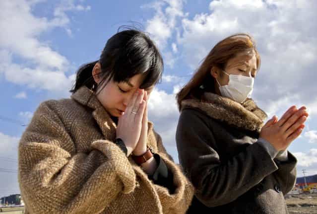 People offer prayers during a moment of silence in front of what is left of a disaster control center in an area devastated by the March 11, 2011 earthquake and tsunami in Minamisanriku, Miyagi Prefecture. Japan marked the second anniversary of the devastating disasters that left nearly 19,000 people dead or missing. (Photo by Shizuo Kambayashi/Associated Press)