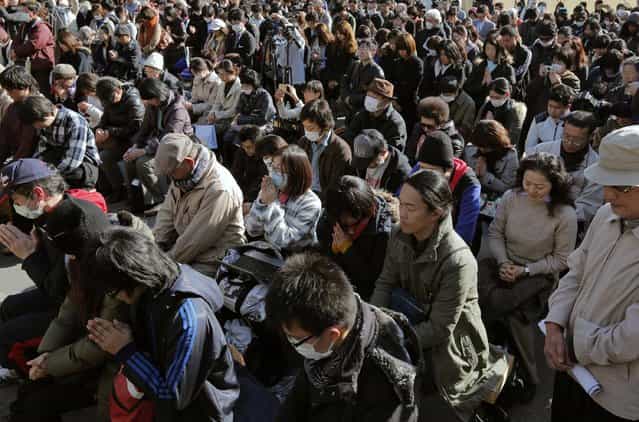 People observe a moment of silence for the victims of the March 11, 2011 earthquake and tsunami during an event at a park in Tokyo, at 2:46 p.m. on Monday. (Photo by Itsuo Inouye/AP Photo)