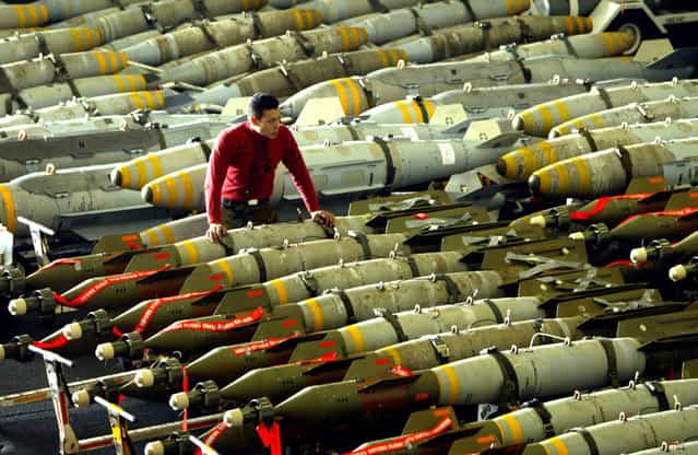 An aviation ordnance man observes rows of bombs on the hangar bay of the USS Kitty Hawk aircraft carrier in the northern Gulf, on March 30, 2003. The carriers airwing flew 104 total sorties over Iraq on March 29, and dropped bombs on targets including air defense sites, a train loaded with tanks and a surface-to-air missile site. (Photo by Paul Hanna/Reuters/The Atlantic)