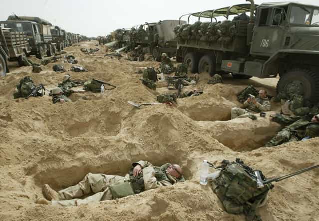 Soldiers from the 3rd Brigade of the U.S. 101st Airborne Division rest in foxholes by their convoy in a staging area in the Kuwaiti desert, on, March 21, 2003. (Photo by Jean-Marc Bouju/AP Photo/The Atlantic)