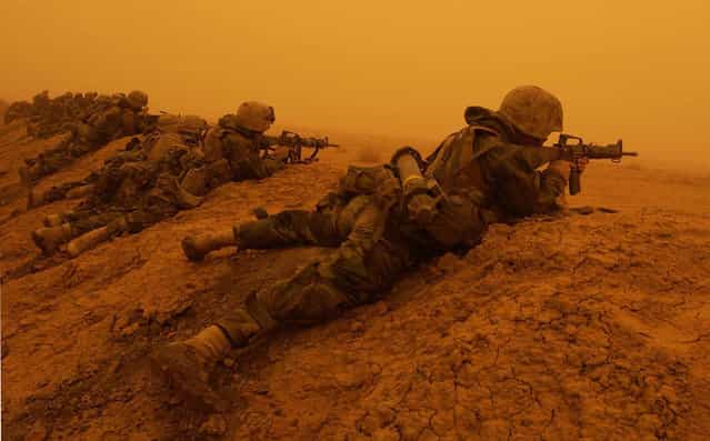 U.S. Marines with 3rd Battalion, 7th Marines, 1st Marine Division, return fire after coming upon a mortar attack during an orange sandstorm on a road south of Baghdad, on March 26, 2003. (Photo by Laura Rauch/AP Photo/The Atlantic)