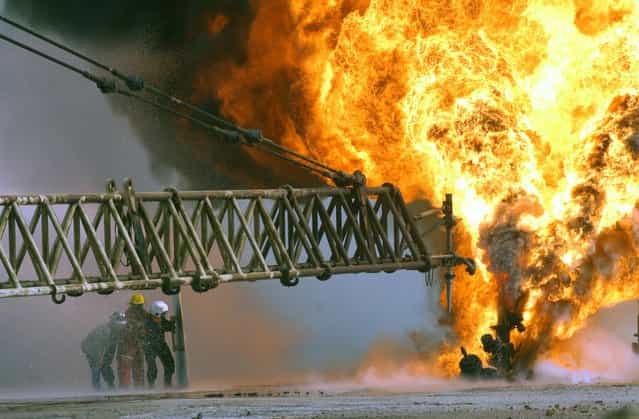 Kuwaiti firefighters secure a burning oil well in the Rumaila oilfields, on March 27, 2003, set ablaze by Iraqi military forces. (Photo by Mary Rose Xenikakis/USMC/The Atlantic)