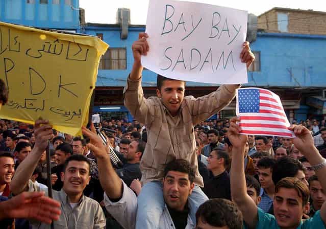 Iraqi Kurds wave banners and U.S. and British flags in the northern Iraqi town of Dohuk, on April 9, 2003, to celebrate the arrival of U.S. led coalition forces' in Baghdad. Iraqi Kurds shouted for joy and fired in the air on Wednesday after U.S. forces entered Baghdad. [It's all over in Baghdad], said 29-year-old Rafiq Baway, who heard the news on satellite TV in the city of Sulaimaniya. He believed it would lead to the fall of Kirkuk, the northern oil hub where Kurds accuse Saddam of expelling Kurdish inhabitants and replacing them with Arabs. (Photo by Reuters/The Atlantic)