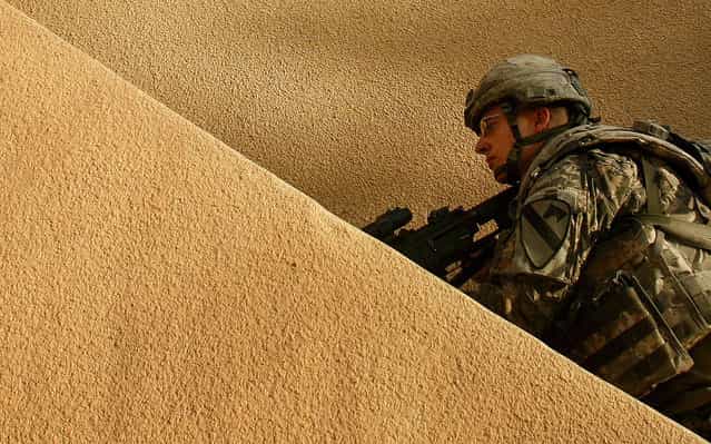 U.S. Army Pvt. Joe Armstrong of Alpha Company, 1st Battalion, 5th Cavalry Regiment, 2nd Brigade, 1st Cavalry Division searches the rooftop of a house during an operation in the Amariyah neighborhood of west Baghdad, Iraq, on Monday, August 13, 2007. (Photo by Petr David Josek/AP Photo/The Atlantic)