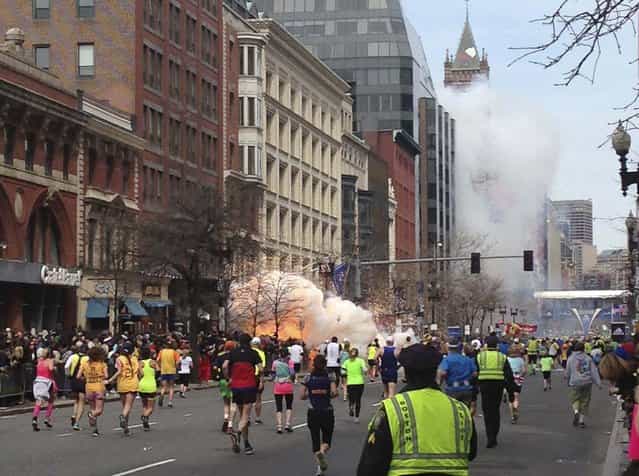 Runners continue to run towards the finish line of the Boston Marathon as an explosion erupts near the finish line of the race in this photo exclusively licensed to Reuters by photographer Dan Lampariello after he took the photo in Boston, Massachusetts, April 15, 2013. (Photo by Dan Lampariello/Reuters)