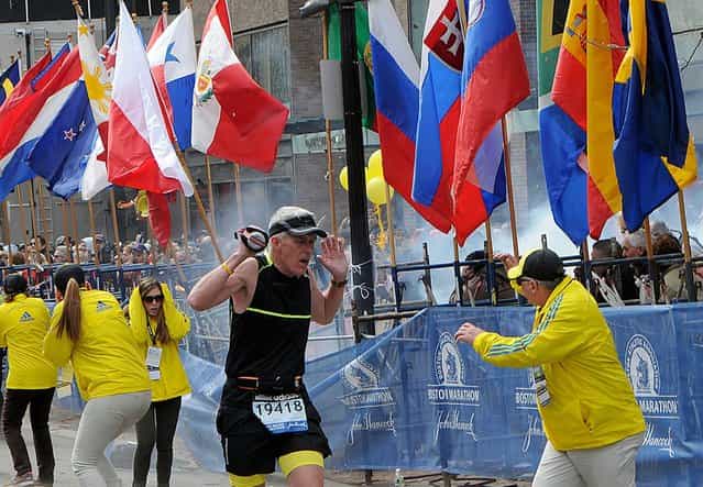 A runner and race officials react to an explosion during the Boston Marathon in Boston, Massachusetts, April 15, 2013. (Photo by Ken McGagh/Reuters/MetroWest Daily News)