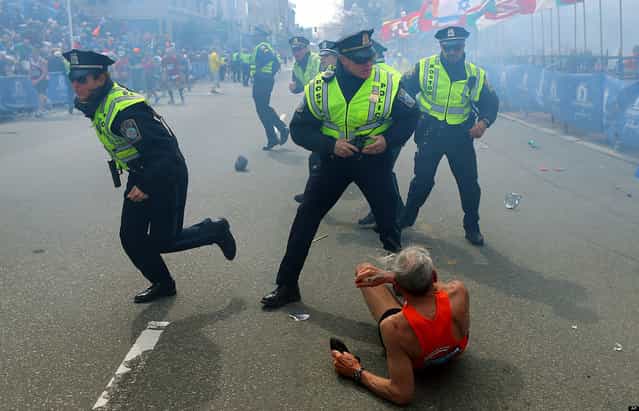 Police officers react to a second explosion at the finish line of the Boston Marathon in Boston, Monday, April 15, 2013. (Photo by John Tlumacki/AP Photo/The Boston Globe)