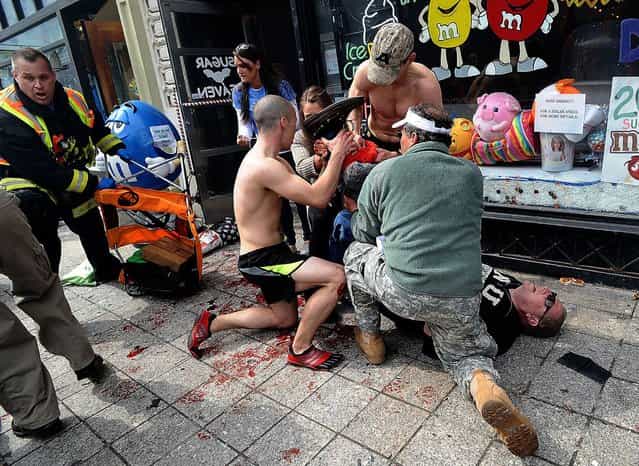 Bystanders tend to an injured man following explosions at the Boston Marathon in Boston, Massachusetts, April 15, 2013. (Photo by Ken McGagh/Reuters/MetroWest Daily News)