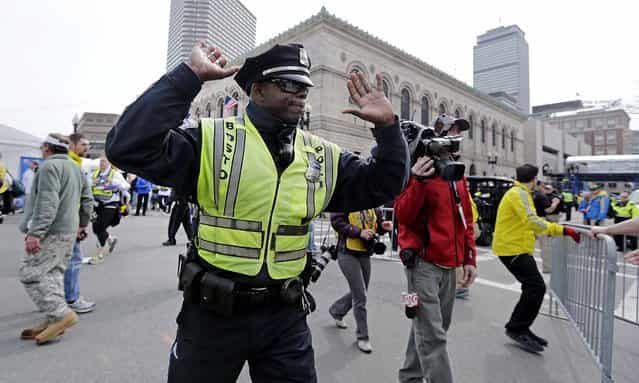 A Boston police officer clears Boylston Street following the explosions. (Photo by Charles Krupa/Associated Press)