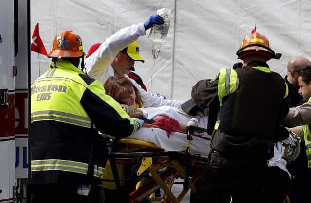 An injured woman is loaded into an ambulance in the aftermath of the two blasts. (Photo by Elise Amendola/Associated Press)