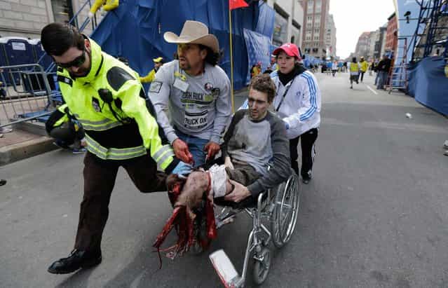 Medical responders run an injured man past the finish line of the 2013 Boston Marathon following two explosions that killed at least two people and injured more than twenty others. (Photo by Charles Krupa/Associated Press)