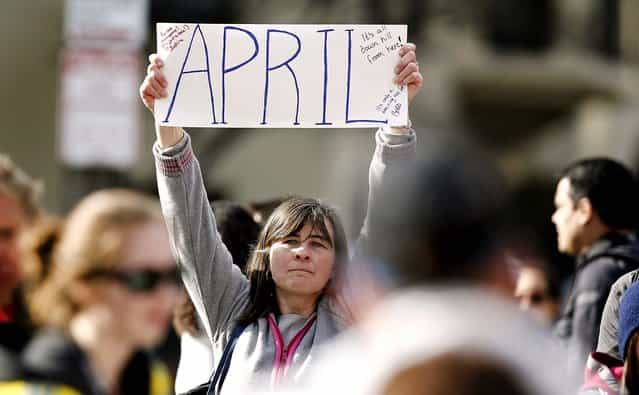 Justine Franco of Montpelier, Vt., holds up a sign near Copley Square, looking for her missing friend, April, who was running in her first Boston Marathon. (Photo by Winslow Townson/Associated Press)