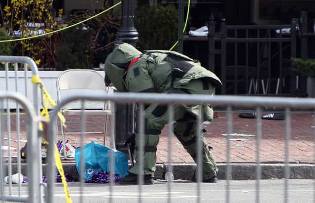 A member of the bomb squad investigates a suspicious item on the road near Kenmore Square after two bombs exploded during the 117th Boston Marathon on April 15, 2013 in Boston, Massachusetts. (Photo by Alex Trautwig)
