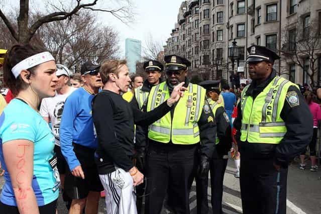 Runners talk to Boston Police near Kenmore Square after two bombs exploded during the 117th Boston Marathon on April 15, 2013 in Boston, Massachusetts. (Photo by Alex Trautwig)