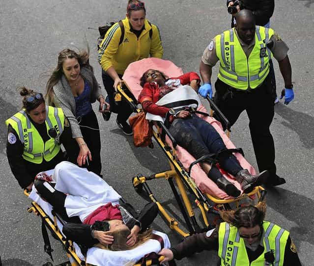 A person who was injured in an explosion near the finish line of the 117th Boston Marathon is taken away from the scene on a stretcher. (Photo by David L. Ryan/The Boston Globe)