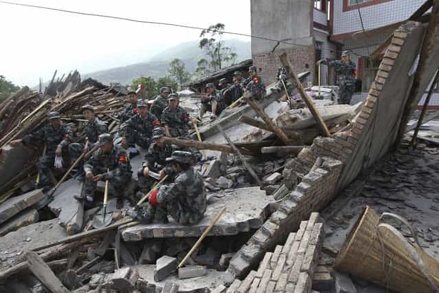Rescue workers sit on the debris of destroyed houses after a strong 6.6 magnitude earthquake, at Longmen village, Lushan county, Ya'an, Sichuan province April 20, 2013. (Photo by Reuters/Stringer)