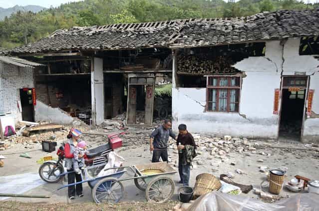 People stand outside a damaged house after a strong 6.6 magnitude earthquake hit, at Longmen village, Lushan county, Ya'an, Sichuan province April 20, 2013. The earthquake hit a remote, mostly rural and mountainous area of southwestern China's Sichuan province on Saturday, killing at least 102 people and injuring about 2,200 close to where a big quake killed almost 70,000 people in 2008. (Photo by Reuters/Stringer)