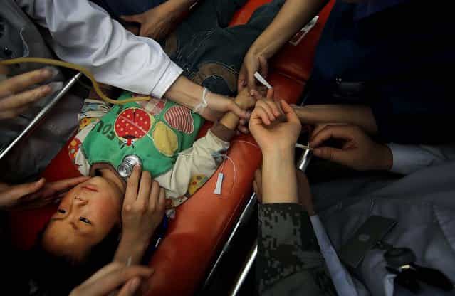 An injured child is examined at a makeshift hospital at the county seat of Lushan in southwestern China's Sichuan province, on April 21, 2013. (Photo by Associated Press)