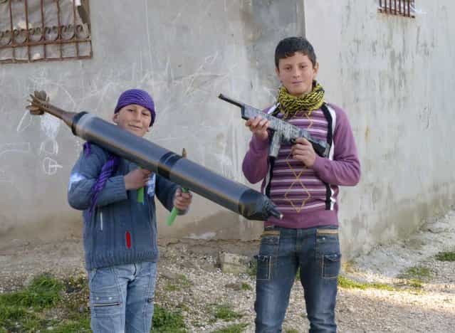 Boys hold up toy guns in the town of Hula near the city of Homs March 2, 2012. (Photo by Reuters)