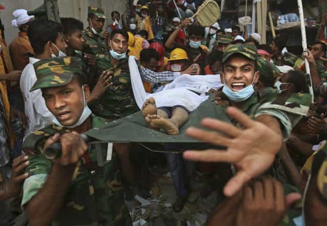 Bangladesh soldiers carry a woman survivor from the rubble at the site of a building that collapsed Wednesday in Savar, near Dhaka, Bangladesh, Thursday, April 25, 2013. By Thursday, the death toll reached at least 194 people as rescuers continued to search for injured and missing, after a huge section of an eight-story building that housed several garment factories splintered into a pile of concrete. (Photo by Kevin Frayer/AP Photo)