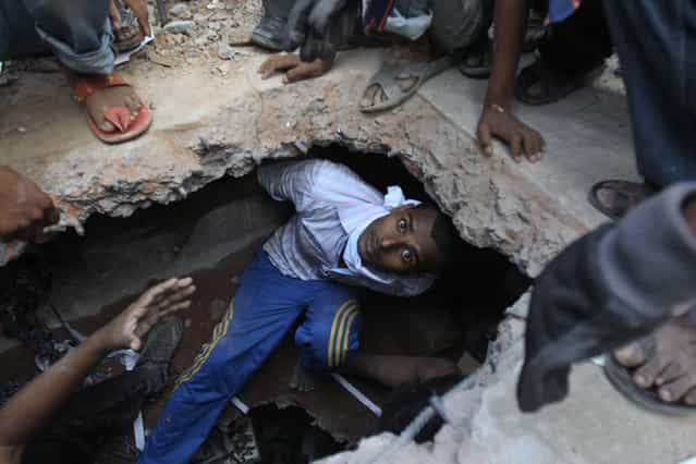 A Bangladeshi rescuer looking for survivors emerges from beneath a concrete slab of a building that collapsed Wednesday in Savar, near Dhaka, Bangladesh, Thursday, April 25, 2013. By Thursday, the death toll reached at least 194 people as rescuers continued to search for injured and missing, after a huge section of an eight-story building that housed several garment factories splintered into a pile of concrete on Wednesday. (Photo by A. M. Ahad/AP Photo)