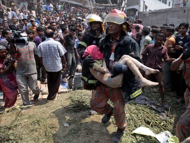 Rescue workers carry a child's body from the scene on Wednesday. (Photo by A. M. Ahad/Associated Press)