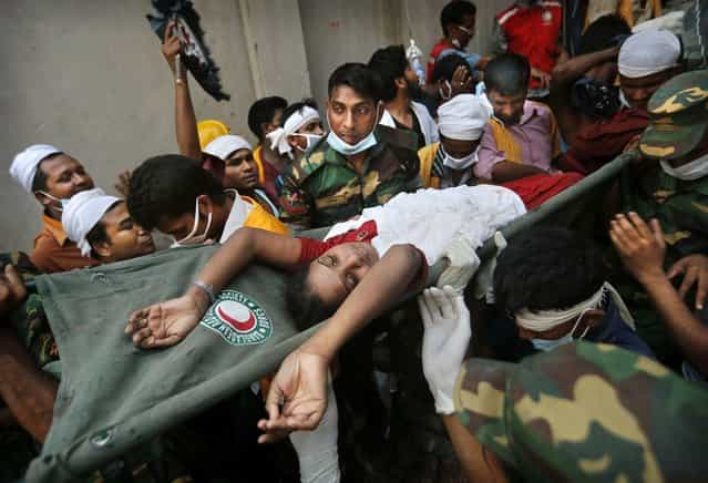 A Bangladeshi woman survivor is carried from the rubble by rescuers at the site of a building that collapsed Wednesday in Savar, near Dhaka, Bangladesh, Thursday, April 25, 2013. By Thursday, the death toll reached at least 194 people as rescuers continued to search for injured and missing, after a huge section of an eight-story building that housed several garment factories splintered into a pile of concrete. (Photo by Kevin Frayer/AP Photo)