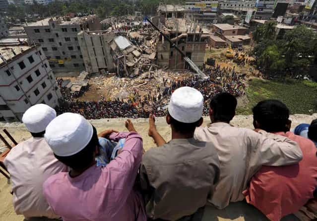 People watch as rescue workers continue their operations at the collapsed Rana Plaza building in Savar, 30 km (19 miles) outside Dhaka April 25, 2013. Survivors from the garment factory that collapsed in Bangladesh killing at least 228 people described on Thursday a deafening bang and tremors before the eight-floor building crashed down under them. (Photo by Reuters/Stringer)