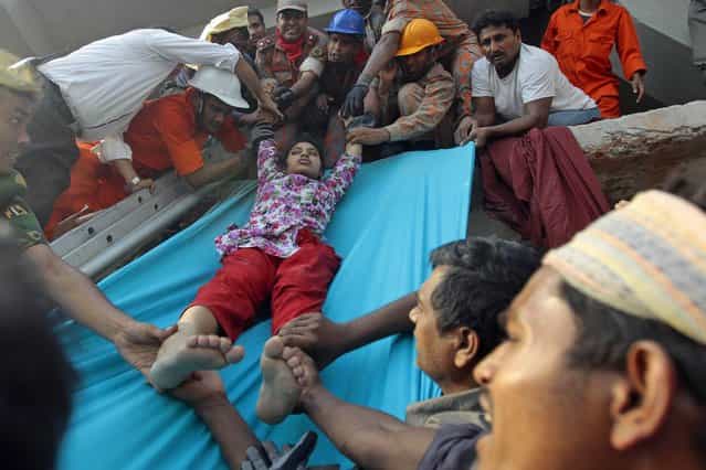 Rescuers lower down a survivor from the debris of a building that collapsed in Savar, near Dhaka, Bangladesh, Wednesday, April 24, 2013. An eight-storey building housing several garment factories collapsed near Bangladesh's capital on Wednesday, killing dozens of people and trapping many more under a jumbled mess of concrete. Rescuers tried to cut through the debris with earthmovers, drilling machines and their bare hands. (Photo by A. M. Ahad/AP Photo)