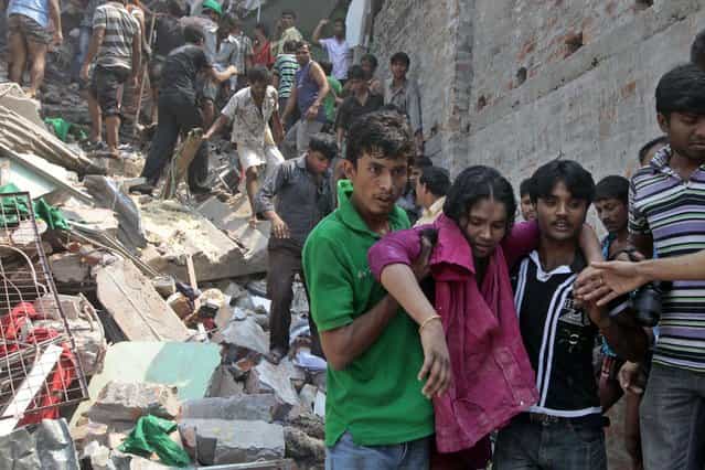 Rescuers assist an injured woman after an eight-story building housing several garment factories collapsed in Savar, near Dhaka, Bangladesh, Wednesday, April 24, 2013. Dozens were killed and many more are feared trapped in the rubble. (Photo by A. M. Ahad/AP Photo)