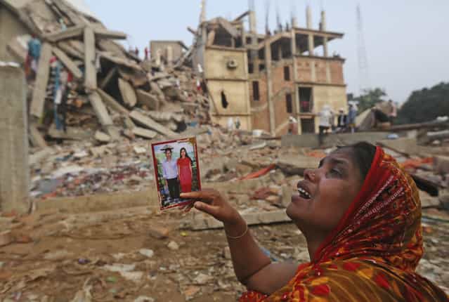 A Bangladeshi woman weeps as she holds a picture of her and her missing husband as she waits at the site of a building that collapsed Wednesday in Savar, near Dhaka, Bangladesh, Friday, April 26, 2013. The death toll reached hundreds of people as rescuers continued to search for injured and missing, after a huge section of an eight-story building that housed several garment factories splintered into a pile of concrete. (Photo by Kevin Frayer/AP Photo)