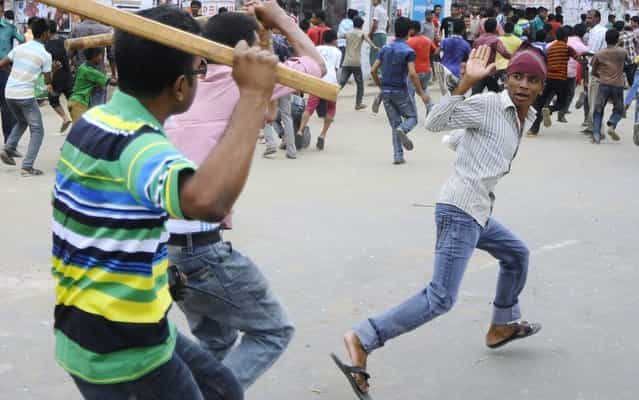 Plain-clothed Bangladeshi police brandish sticks as they attempt to break up demonstrating garment workers following the collapse of an eight-storey building, in Dhaka on April 26, 2013. Bangladeshi police battled April 26 to control huge crowds of garment workers angrily protesting the death of more than 300 colleagues in a collapsed building as rescue efforts stretched into a third day. (Photo by AFP Photo/STR)