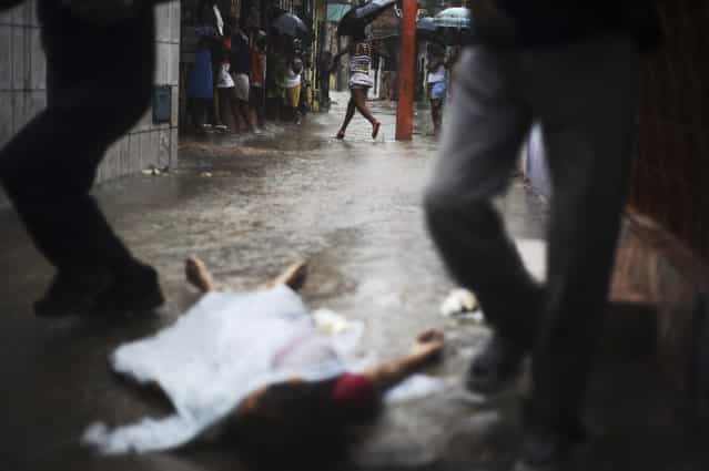 The body of a person identified by the police as a tranvestite named Rodrigo, lies on the street where he was shot in the Alto do Cabrito slum of Salvador, Bahia State, March 30, 2013. One of Brazil's main tourist destinations and a 2014 World Cup host city, Salvador suffers from an unprecedented wave of violence with an increase of over 250% in the murder rate, according to the Brazilian Center for Latin American Studies (CEBELA). (Photo by Lunae Parracho/Reuters)
