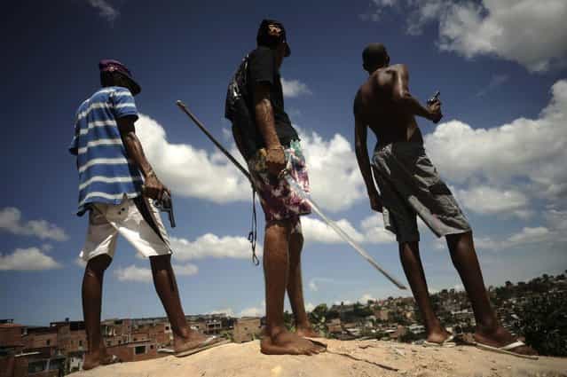 Brazilian drug gang members pose with weapons atop a hill overlooking a slum in Salvador, Bahia State, April 11, 2013. (Photo by Lunae Parracho/Reuters)