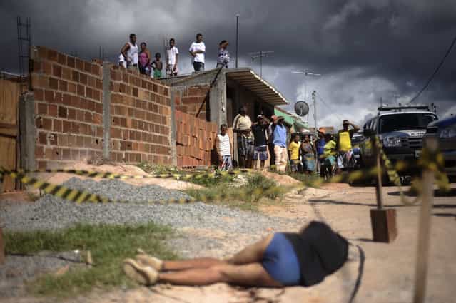 Residents observe the body of a person shot in the head in the Sao Cristovao slum of Salvador, Bahia State, April 13, 2013. One of Brazil's main tourist destinations and a 2014 World Cup host city, Salvador suffers from an unprecedented wave of violence with an increase of over 250% in the murder rate, according to the Brazilian Center for Latin American Studies (CEBELA). (Photo by Lunae Parracho/Reuters)
